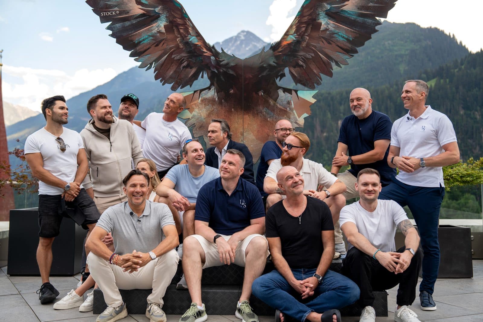 Gruppenfoto bei einem früheren Summit vor einer Adler-Skulptur und Bergpanorama
