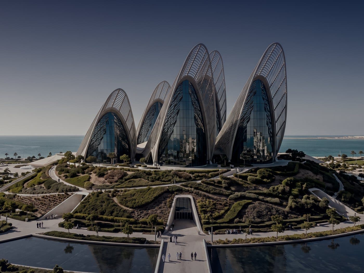 Symbolbild: ein modernes Museum mit geschwungenen, flügelartigen Türmen am Wasser in Abu Dhabi