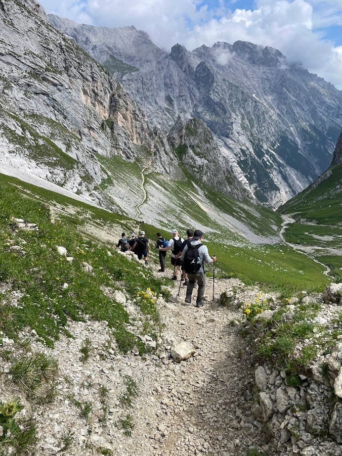 Eine Gruppe wandert auf einem steinigen Pfad durch ein Hochgebirgstal