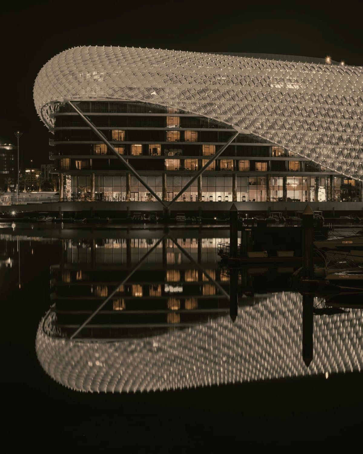 Das beleuchtete Yas Hotel in Abu Dhabi bei Nacht, gespiegelt im Wasser