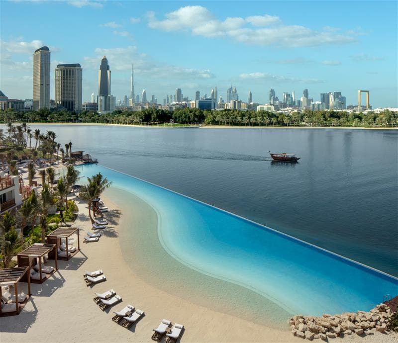 Infinity-Pool und Strand des Park Hyatt Dubai am Wasser, dahinter die Skyline von Dubai