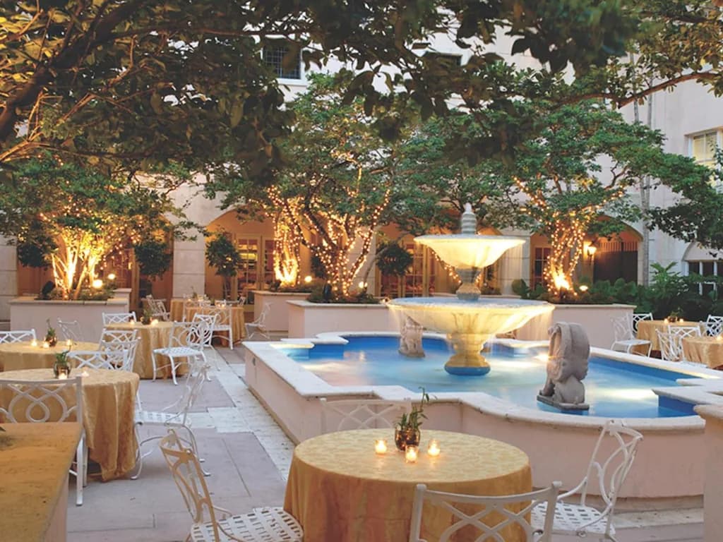 Innenhof mit Brunnen und gedeckten Tischen in der Abenddämmerung
