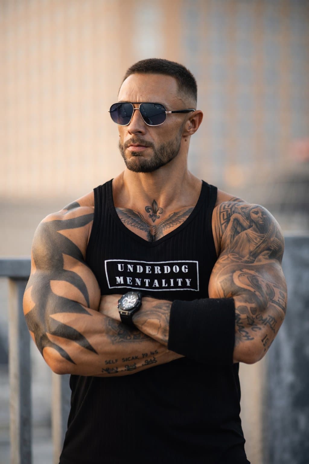 Muskulöser Mann mit Sonnenbrille und Underdog-Mentality-Shirt, Arme verschränkt